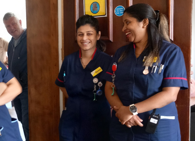A photo of two nursing members of our staff, stood in the doorway smiling