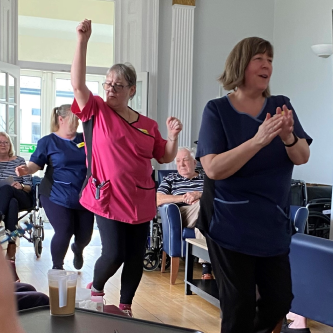 Photo of our staff members dancing through the lounge entertaining our residents