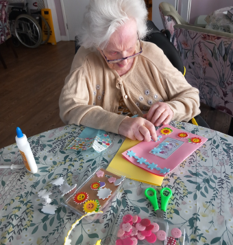 One of our residents sat at a table with card decorating accessories and scissors, decorating her own card