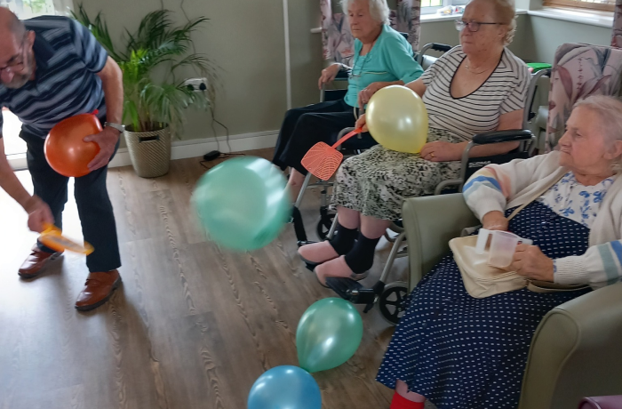 Residents sat in chairs playing a game involving swatting balloons