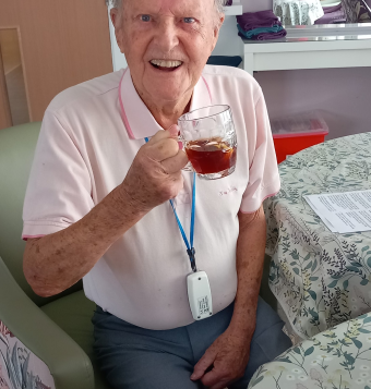 One of our residents sat at a table with a glass mug in hand, smiling at the camera
