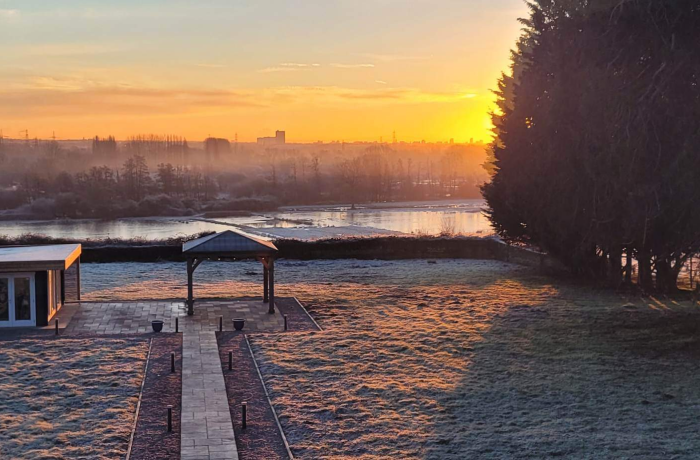 A wintery photo of the grounds at Colbury House during a misty winter sunrise with frost on the grass